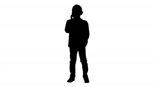Silhouet schattige kleine jongen praten op zijn smartphone en staande in een donker pak. — Stockvideo