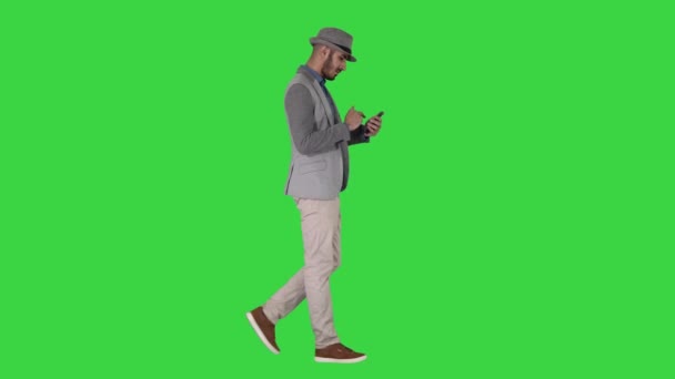 Serieuze Arabisch casual man het gebruik van smartphone tijdens het lopen op een groen scherm, Chroma Key. — Stockvideo