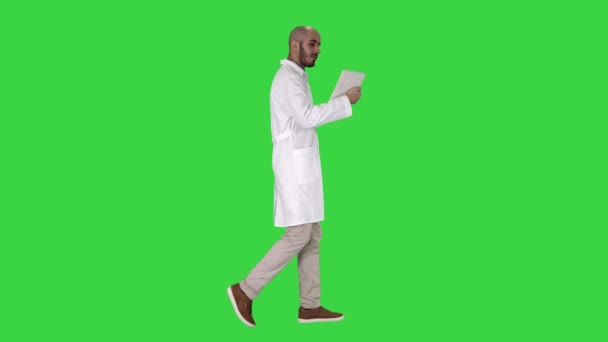 Ειλικρινής γιατρός κάνοντας βιντεοκλήση στον ασθενή του περπατώντας σε πράσινη οθόνη, πλήκτρο αποχρώσεων. — Αρχείο Βίντεο