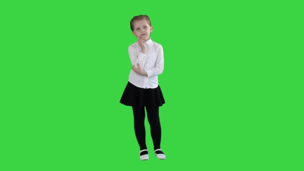 Een nieuwsgierig meisje staat en denkt op een groen scherm, Chroma Key. — Stockvideo