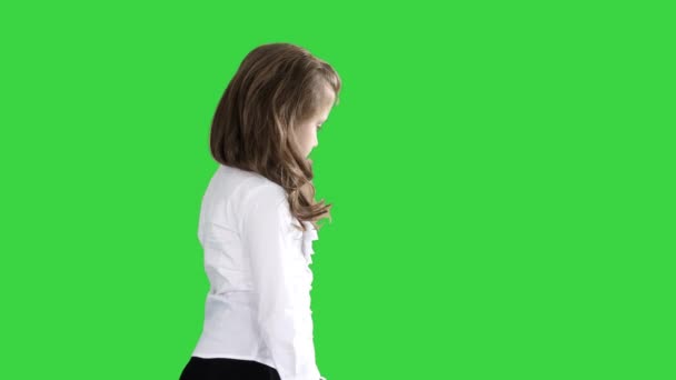 Маленька дівчинка з довгим волоссям ходьбі і дивлячись на зелений екран, ключ до кольоровості. — стокове відео