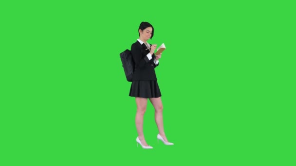 Όμορφη μαθήτρια με σακίδιο που γράφει σημειώσεις σε μια πράσινη οθόνη, Chroma Key. — Αρχείο Βίντεο