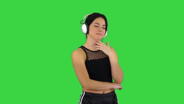 Junge sportliche schöne Frau genießt die Musik in Kopfhörern auf einem Green Screen, Chroma Key. — Stockvideo