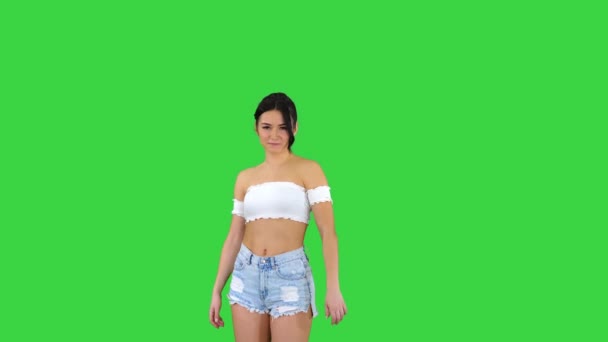 Bedårande hispanic kvinnlig modell i denim shorts dansar på en grön skärm, Chroma Key. — Stockvideo