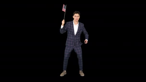 Молода людина в офіційному костюмі танцює в смішний спосіб з американським прапором, Альфа-канал — стокове відео