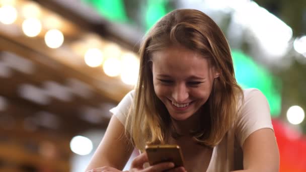 귀여운 여자가 휴대폰으로 웃고 문자 메시지를 보내는 모습. — 비디오