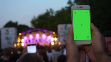 Bulanık konser arka plan önünde telefon kayıt video tutan genç adamın eli.