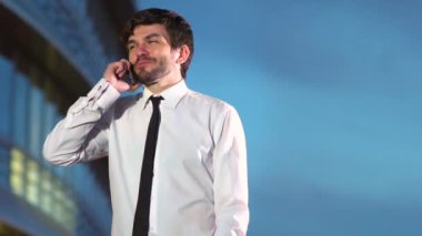 Genç mutlu başarılı işadamı telefonda gülümseyerek konuşuyor.