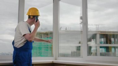 İnşaat alanındaki inşaat işçisi, vinç işi hakkında tavsiye vermek için meslektaşlarını arıyor..