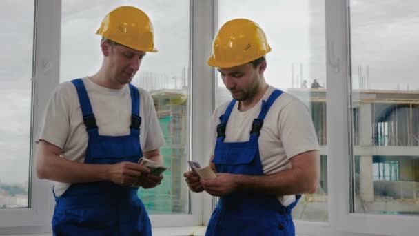 Construtores em capacetes contando salário. — Vídeo de Stock