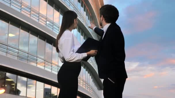 Homem de negócios e mulher olhando para o centro de negócios discutindo sua arquitetura . — Vídeo de Stock