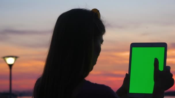 Γυναίκα που κρατά και χρησιμοποιεί ψηφιακό δισκίο στο ηλιοβασίλεμα. — Αρχείο Βίντεο