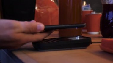 Ahşap bir masa üzerinde ödeme ifade etmek için akıllı telefon kullanan adam.