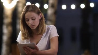 Açık hava kafede oturan bir tablet kullanarak genç kız.