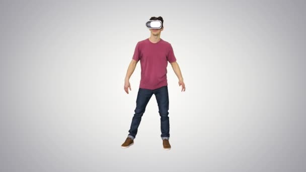 Casual man in VR glasses dancing playing video game Beginners level on gradient background. — Stock Video