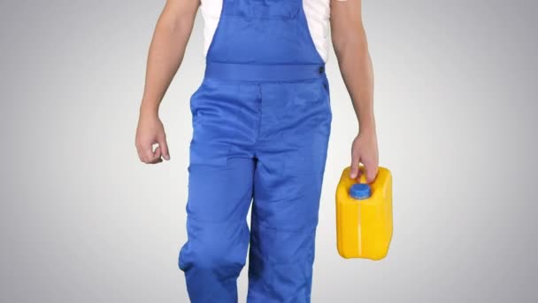 Construction worker in hard hat holding plastic canister and walking on gradient background. — Stock Video