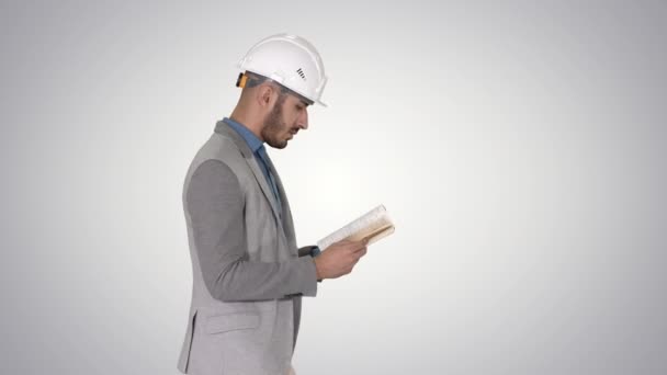 Junger Architekt liest Lehrbuch oder Notizbuch, während er auf dem Gefällehintergrund geht. — Stockvideo