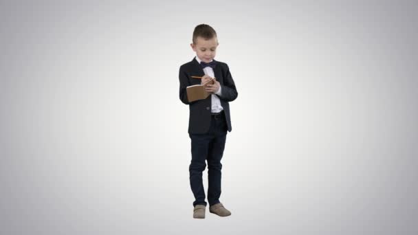 Junge in formeller Kleidung schreibt in Checkliste oder Notizbuch auf dem Hintergrund des Gefälles. — Stockvideo