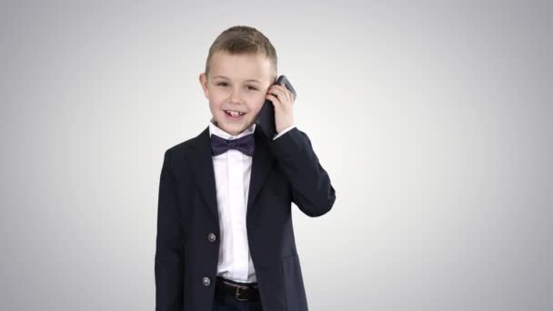 Маленький мальчик в костюме делает телефонный звонок, идя по градиентному фону. — стоковое видео