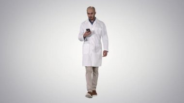 Degrade arka planda yürürken telefonda erkek arap doktor mesajlaşma mesajı.