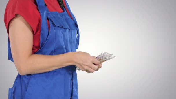 En kvinna i en arbetare kläder räknar pengar på lutning bakgrund. — Stockvideo
