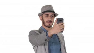 Günlük kıyafetleriyle yürüyen ve beyaz arka planda selfie çeken Arap bir adam..