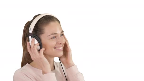 Joven hermosa mujer en traje brillante disfrutando de la música sobre fondo blanco . — Vídeos de Stock