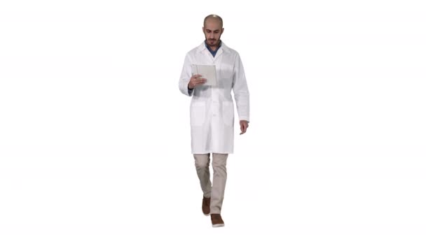 Ώριμος άνδρας γιατρός κρατώντας ψηφιακό δισκίο χρησιμοποιώντας το και το περπάτημα σε λευκό φόντο. — Αρχείο Βίντεο