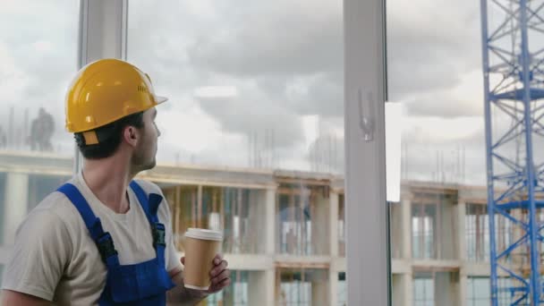 Εργάτης που φοράει καπέλο κάνει διάλειμμα πίνοντας καφέ.. — Αρχείο Βίντεο