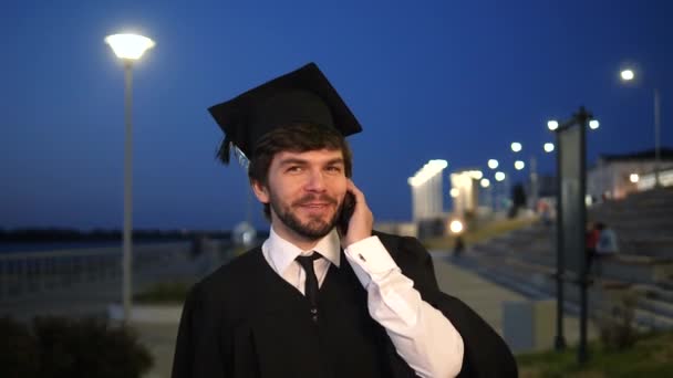 Étudiant diplômé marche et passe un appel. — Video