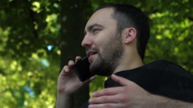 Caddede cep telefonuyla neşeli bir erkek..