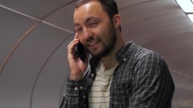 Gündelik gülümseyen adam metroda yürüyen merdivenle telefonda konuşmayı bitirir.
