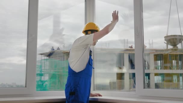 Arbeiter blickt aus dem Fenster auf Baustelle. — Stockvideo