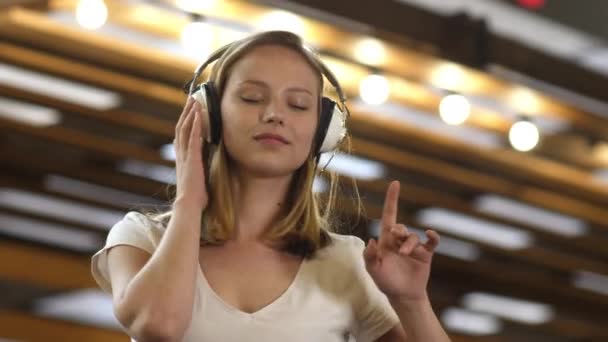 Ung vacker kvinna njuter av musiken i sina hörlurar. — Stockvideo