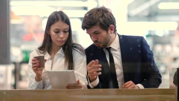 Business man and woman sitting using tablet in a mall. — Stock Video