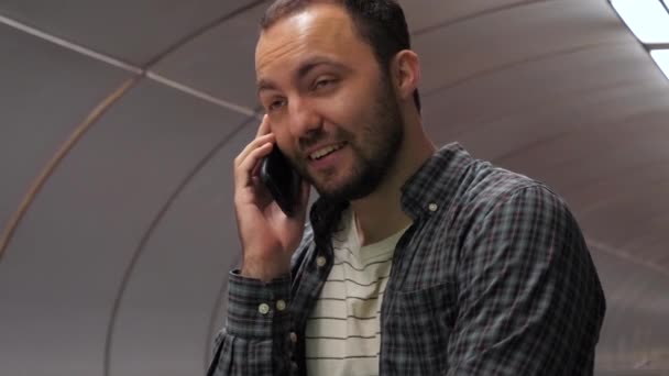 Hombre sonriente casual termina de hablar por teléfono en una escalera mecánica en el metro . — Vídeo de stock