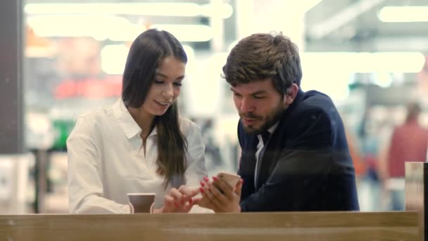 Mutlu iş çifti konuşuyor. Alışveriş merkezindeki akıllı telefona bakıp gülüyorlar.. — Stok video