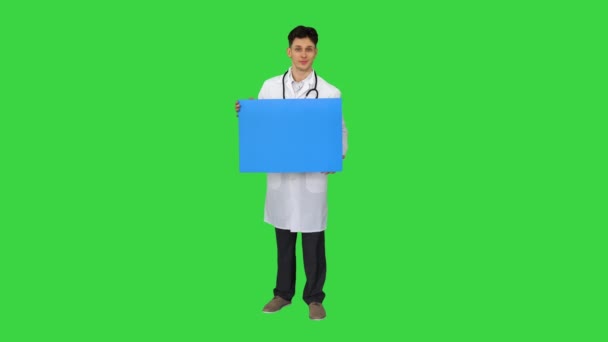 Médico sonriente usando un estetoscopio sosteniendo un cartel en blanco en una pantalla verde, Chroma Key. — Vídeo de stock
