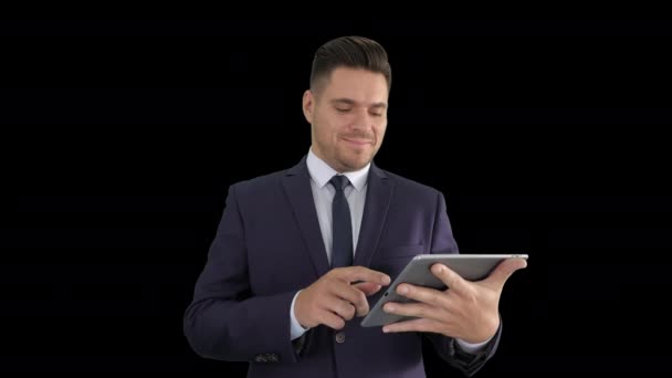 Hombre guapo deslizando páginas en la tableta y sonriendo a la cámara, Alpha Channel — Vídeos de Stock