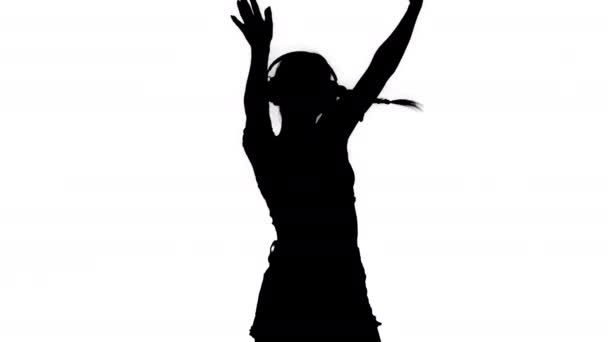 Silhouette Caucasian female model in headphones jumping, expressing happy emotions listening to music. — Stock Video