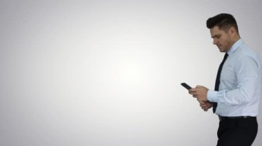 Mutlu iş adamı cep telefonu kullanarak çerçeve içinde yürüyüş ve daha sonra degrade arka plan üzerinde çıkış kazanan jest yapma.