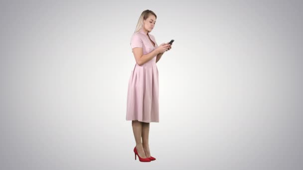 Blonde teenager woman wearing pink texting message on her smartphone on gradient background. — Stock Video