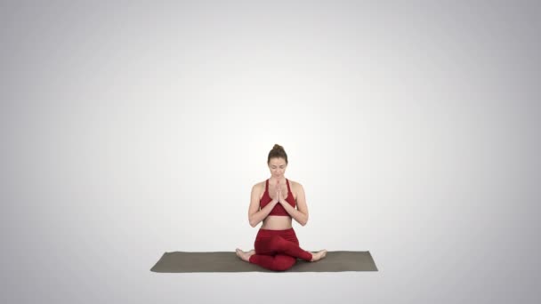 Mladá atraktivní žena trénuje jóga, která sedí v Gomukasaně, na pozadí s přechodem. — Stock video