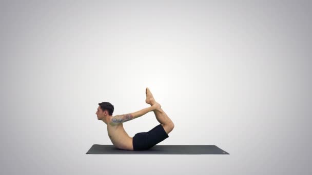 Sportig muskulös ung Yogi man gör backbend övning, Dhanurasana, Bow hållning på gradient bakgrund. — Stockvideo