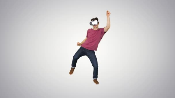 Advanced gamer in casual outfit playing dancing game in VG headset on gradient background. — Stock Video