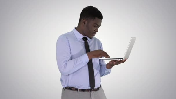 Afro Amerikaanse zakenman werken met laptop op gradiënt achtergrond. — Stockvideo