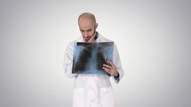Doctor radiologist looking at x-ray scan walking on gradient background. — Stock Video