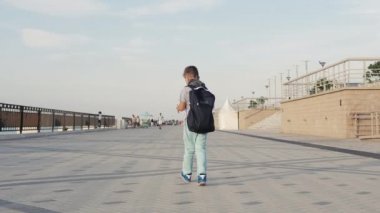 Çocuk bir sırt çantasıyla sokakta yürüyor..