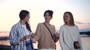 Gün batımında yürüyen ve gülen üç güzel kadın.