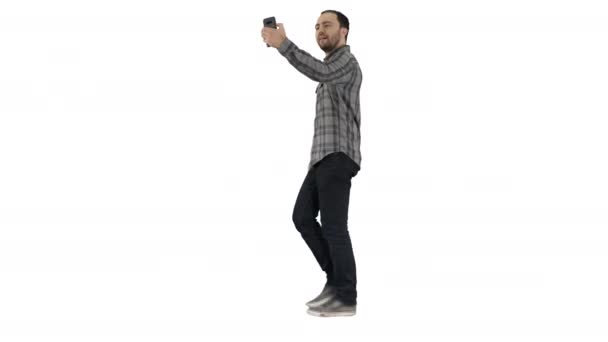 Mutlu gülümseyen, yürüyen yakışıklı, sakallı genç adam beyaz arka planda selfie çekiyor.. — Stok video